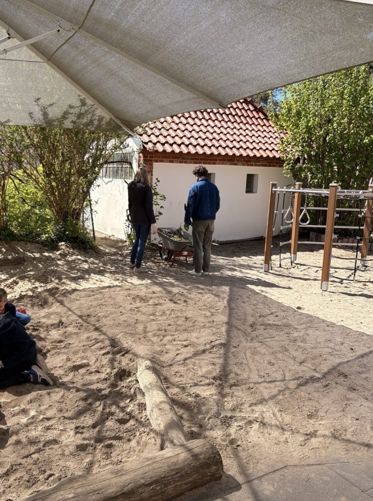 Reparaturwochenende in der Kita - zwei Eltern arbeiten im Garten
